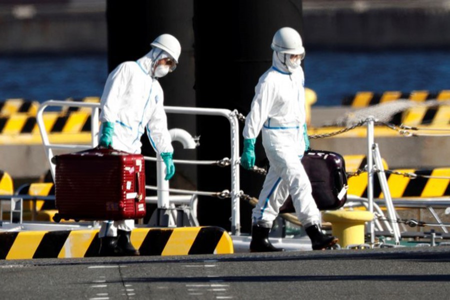 Officers in protective gears carry luggage cases after people who were transferred from cruise ship Diamond Princess, arrive at a maritime police's base in Yokohama, south of Tokyo, Japan on February 5, 2020 — Reuters photo