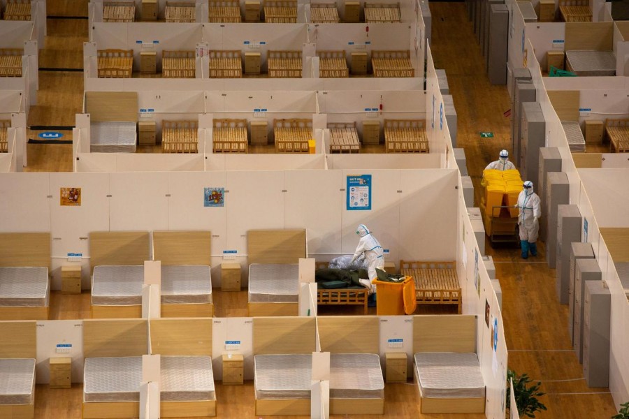 Workers in protective suits remove bed linen inside a closed makeshift hospital which had been converted from a sports stadium, following its last group of patients with coronavirus have been discharged, in Wuhan, the epicentre of coronavirus outbreak, in Hubei province, China on March 8, 2020 — China Daily via Reuters