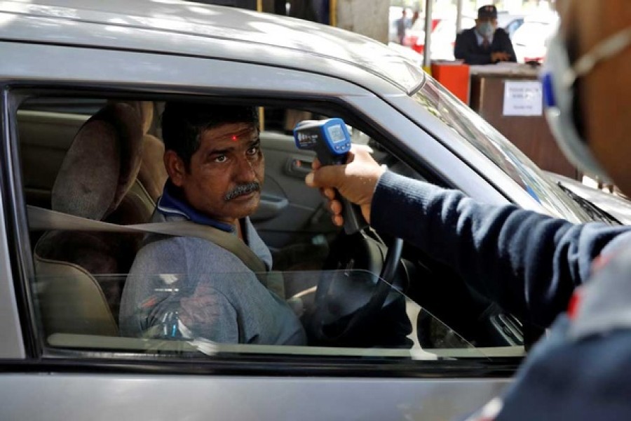 A man arriving into an office building gets his temperature measured by a private security guard using an infrared thermometer, following an outbreak of the coronavirus disease, in New Delhi, India, Mar 9, 2020. REUTERS