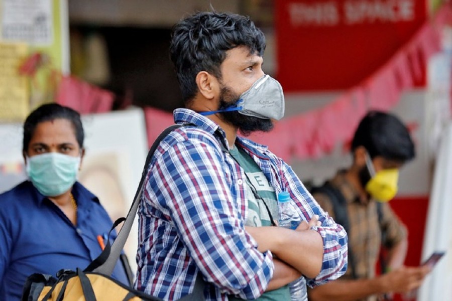 People wearing protective masks wait to board a bus at a terminal amid coronavirus fears, in Kochi, India, March 11, 2020. — Reuters