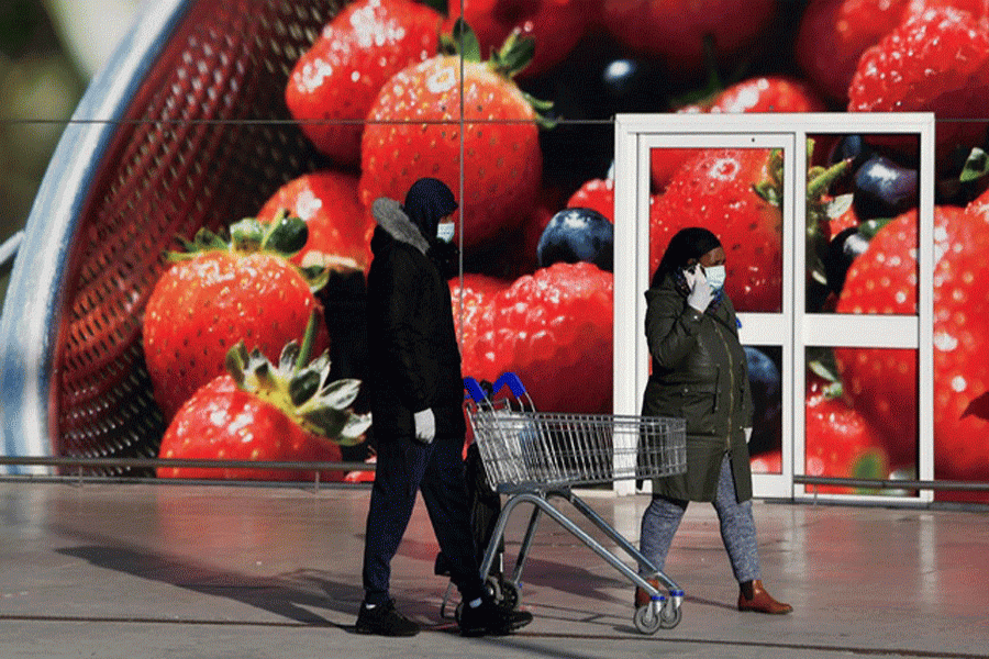 Shoppers wearing protective face masks queue outside a Tesco supermarket as they follow social distancing rules in West London as the spread of the coronavirus disease (COVID-19) continues, in London, Britain, Mar 26, 2020. REUTERS