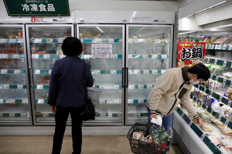 A shopper wearing a protective face mask, following an outbreak of the coronavirus disease (COVID-19), is seen next to an empty shelves of frozen foods at a supermarket in Tokyo, Japan March 27, 2020. REUTERS/Issei Kato