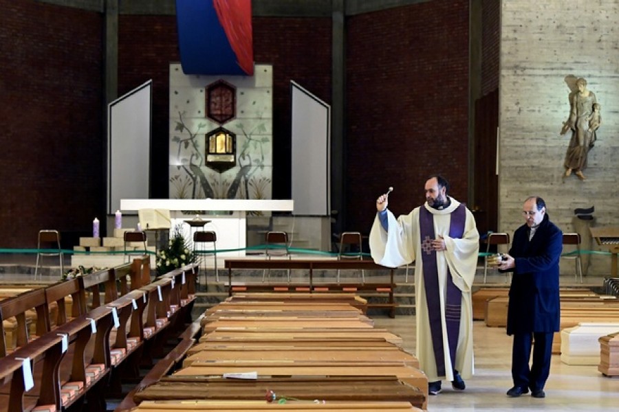 A local priest blesses coffins that have been piling up in a church due to a high number of deaths, before they are taken away by military trucks, as Italy struggles to contain the spread of coronavirus disease (COVID-19), in Seriate, Italy, March 28, 2020. — Reuters