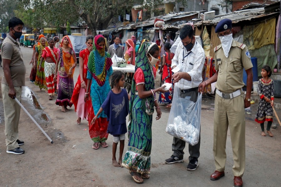 Slum dwellers in Ahmedabad receive free food packets during a 21-day nationwide lockdown - Amit Dave/Reuters