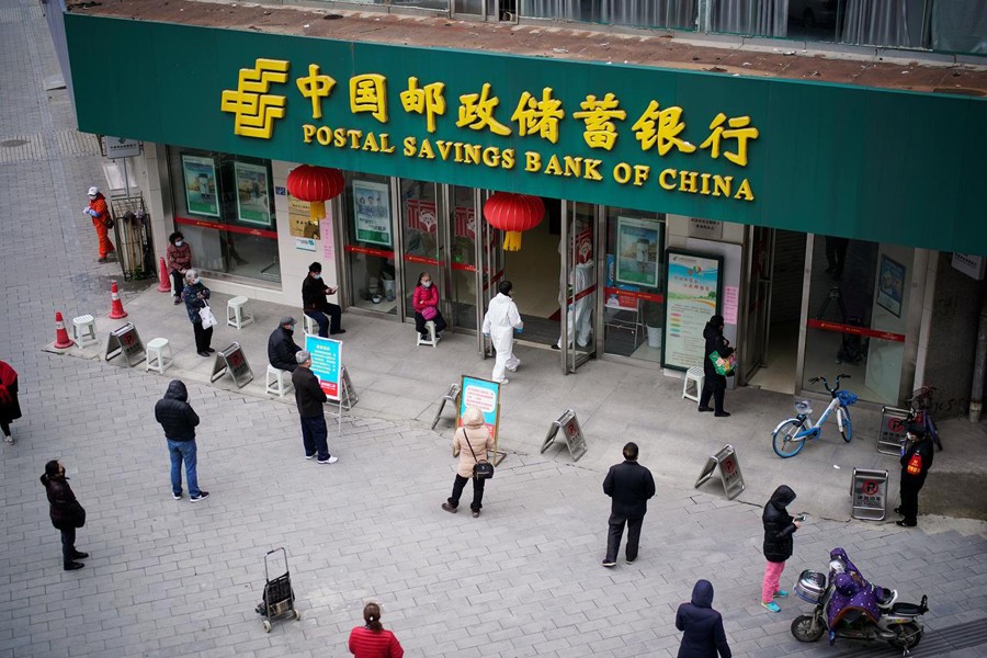 People wearing face masks practise social distancing as they wait outside a Postal Savings Bank of China branch in Wuhan, Hubei province, the epicentre of coronavirus disease (COVID-19) outbreak on March 31, 2020 — Reuters photo