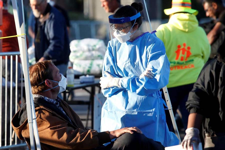 A medical student from Touro University Nevada talking with a man in a temporary parking lot shelter, with spaces marked for social distancing to help slow the spread of coronavirus disease (COVID-19) in Las Vegas, Nevada, US on Monday. There have been 3,415 COVID-19 deaths in the US, more than the 3,309 reported officially in China as of Tuesday. —Photo: Reuters