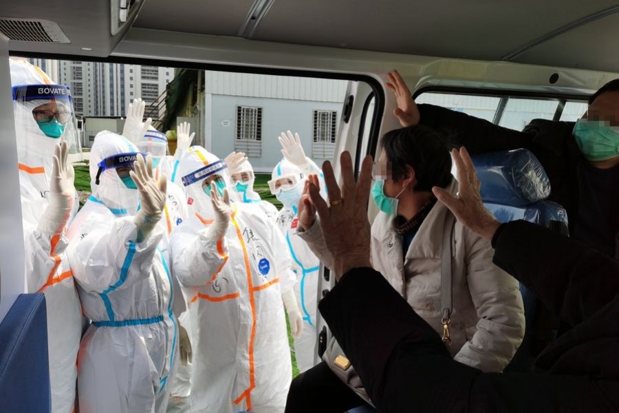 Photo taken with a mobile phone shows cured patients waving goodbye to medical workers before leaving the Leishenshan hospital in Wuhan, central China's Hubei Province, April 4, 2020. (Photo by Gao Xiang/Xinhua)