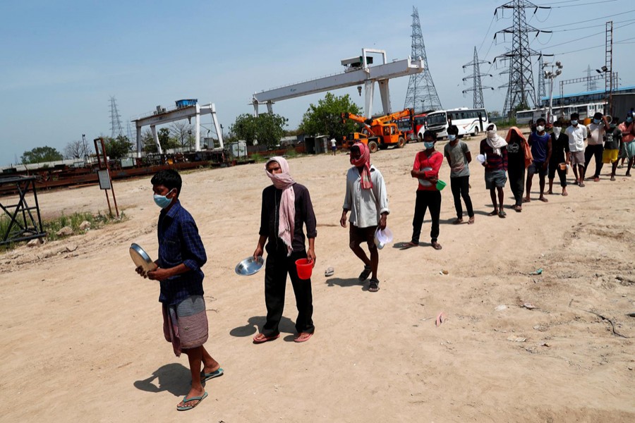 Karan Kumar (2-L) a daily wage labourer, stands in a queue with others for free food at a construction site where activity has been halted due to the nationwide lockdown to slow the spreading of the coronavirus disease (COVID-19), in New Delhi, India on April 10, 2020 — Reuters/Files