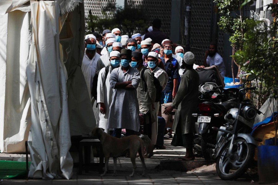 Men wearing protective masks wait for a bus that will take them to a quarantine facility, amid concerns about the spread of coronavirus disease (COVID-19), in Nizamuddin area of New Delhi, India, March 31, 2020. REUTERS/Adnan Abidi