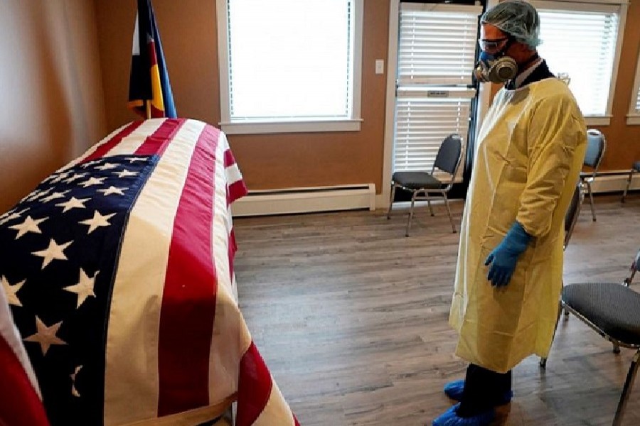 Michael Neel, funeral director of All Veterans Funeral and Cremation, wearing full PPE, looks at the US flag on the casket of George Trefren, a 90-year-old Korean War veteran who died of the coronavirus disease (COVID-19) in a nursing home, in Denver, Colorado, US, April 23, 2020. — Reuters