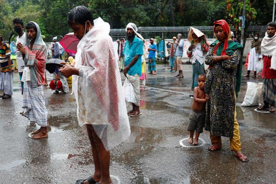 People stand in queues maintaining social distance, for Iftar meals that are distributed by volunteers during Ramadan amid the coronavirus disease (COVID-19) outbreak in Dhaka, Bangladesh, April 28, 2020. Reuters