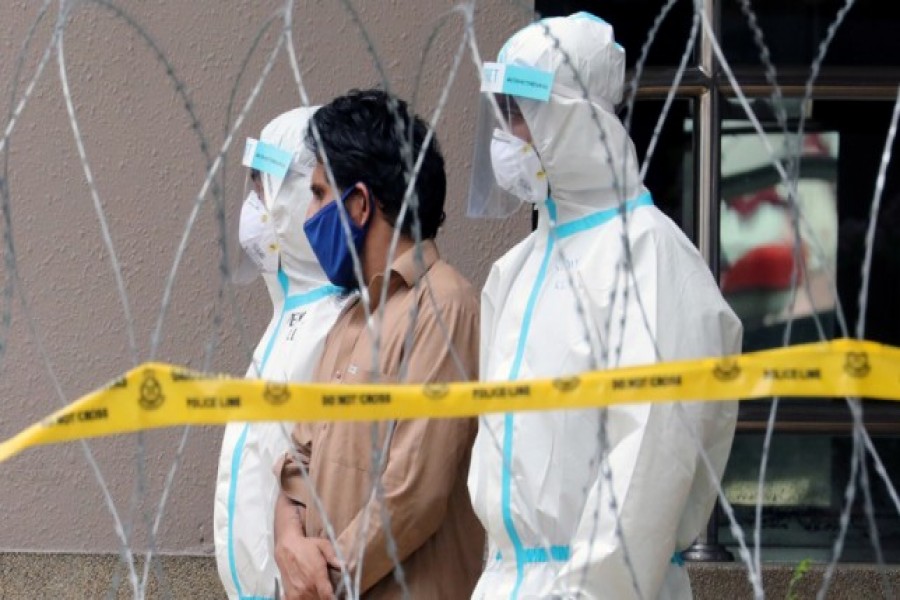 FILE PHOTO: Police officers wearing protective suits pick up an illegal immigrant from an apartment under enhanced lockdown, during the movement control order due to the outbreak of the coronavirus disease (COVID-19), in Kuala Lumpur, Malaysia, May 1, 2020. REUTERS/Lim Huey Teng