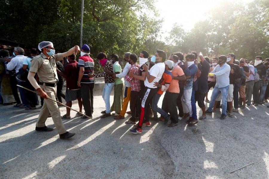 A police officer tries to control the crowds outside a wine store during an extended nationwide lockdown to slow down the spread of the coronavirus disease (COVID-19), in New Delhi, India, May 4, 2020. REUTERS/Adnan Abidi