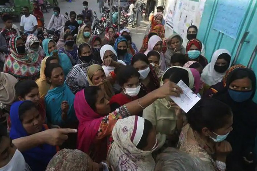 People wait to receive free food for Ramzan during Covid-19 lockdown, in Lahore on Wednesday. (AP Photo)