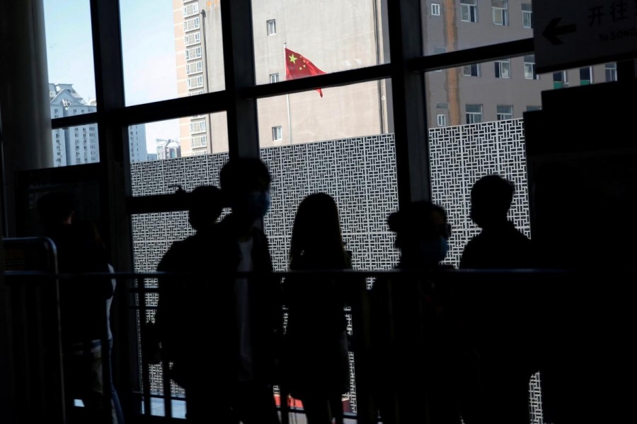 People wearing face masks to prevent the spread of the novel coronavirus disease (COVID-19) walk inside a subway station near a Chinese national flag, on the day of the opening session of the National People's Congress (NPC), in Beijing, China May 22, 2020. REUTERS/Tingshu Wang/File Photo