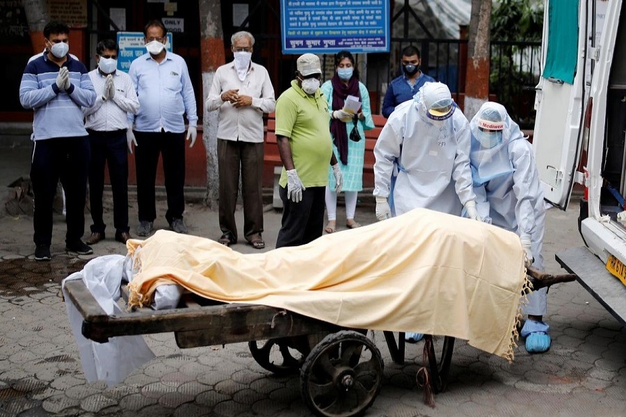 Health workers cover the body of a man who died due to the coronavirus disease (COVID-19), as relatives pay their respects, at a crematorium in New Delhi, India, June 04, 2020. — Reuters