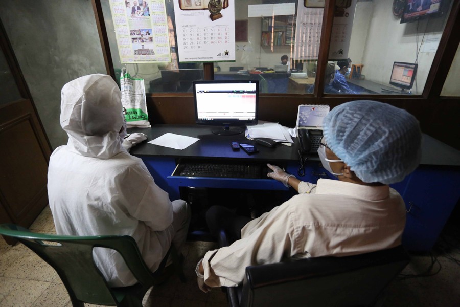 Traders, wearing protective gears, monitoring stock price movements on computer screens at a brokerage house in the capital city — FE/Files