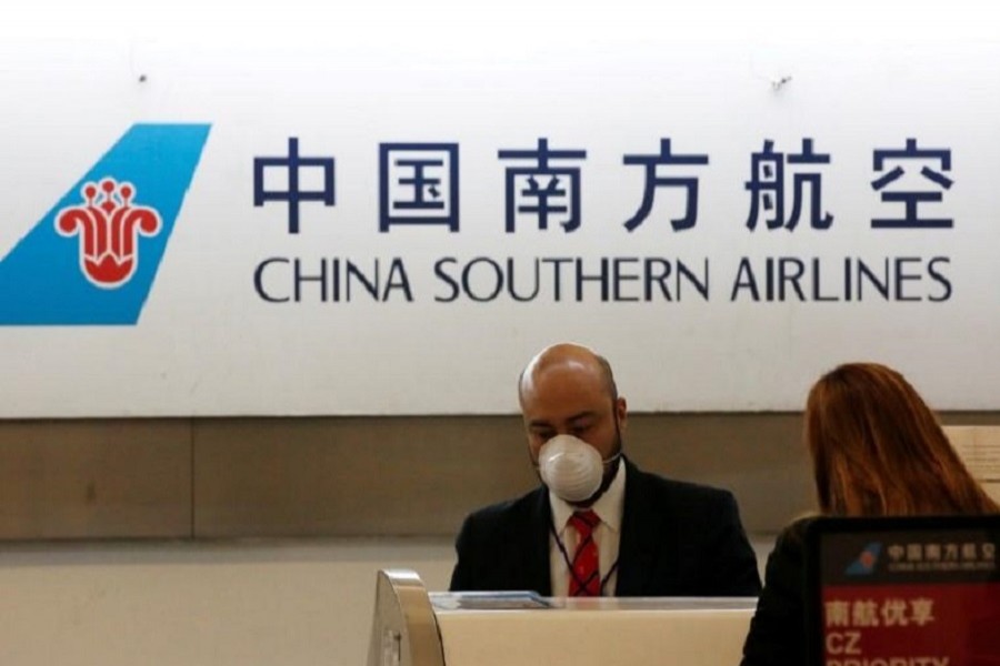 A China Southern Airlines employee wears a surgical mask as a preventive measure in light of the coronavirus outbreak in China, while he attends a customer behind the counter at Benito Juarez international airport in Mexico City, Mexico, January 28, 2020. — Reuters