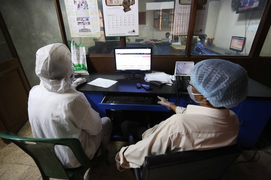 Traders, wearing protective gears, monitoring stock price movements on computer screens at a brokerage house in Dhaka city — FE/Files