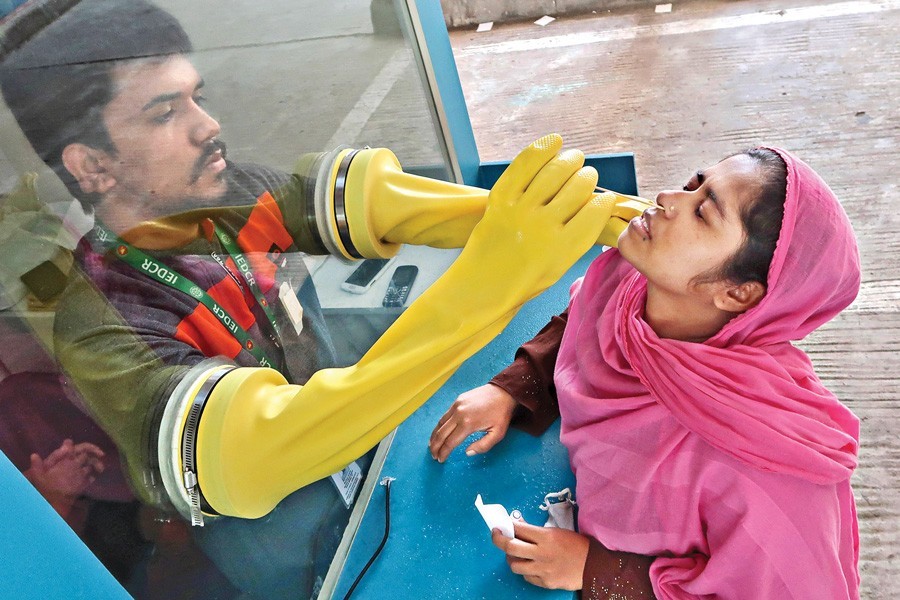 A health worker collecting nasal swabs from a woman at a Covid-19 testing kiosk in Dhaka city on Wednesday — FE photo