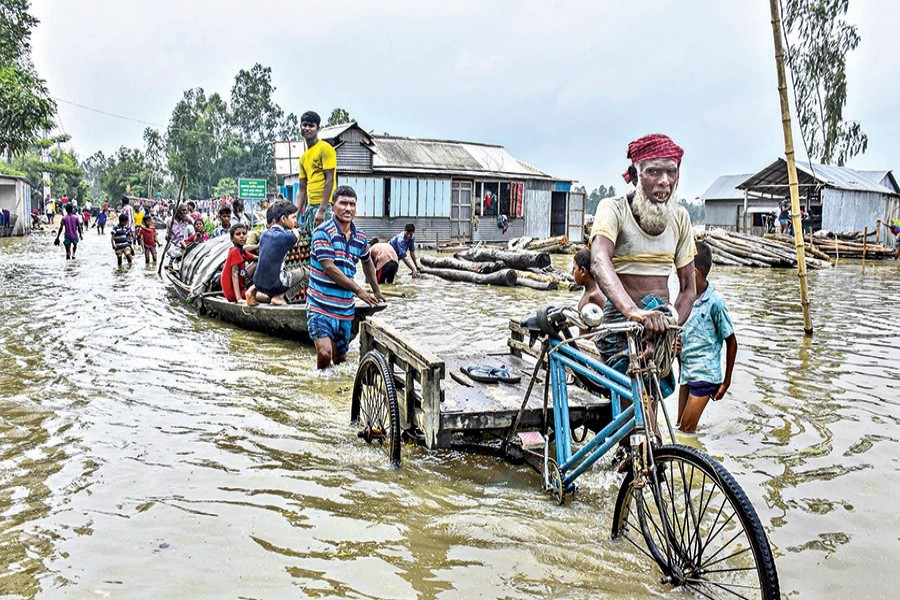 A boat and a van ply the inundated Balashighat Road at Fulchhari in Gaibandha on Saturday as the Brahmaputra is flowing above the danger mark — Focus Bangla