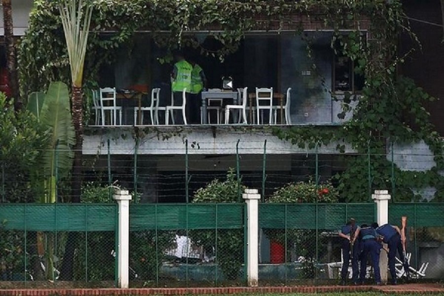 Policemen sneak a look inside the Holey Artisan Bakery and the O'Kitchen Restaurant as others inspect the site after gunmen attacked, in Dhaka, Bangladesh, July 03, 2016 — Reuters/Files