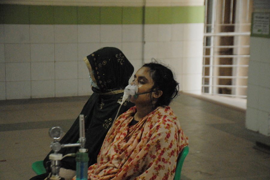 A woman with Covid-19 symptoms, who travelled all the way to Dhaka from Cumilla seeking better treatment, waits at Mugda Medical College Hospital with her oxygen mask on — File photo