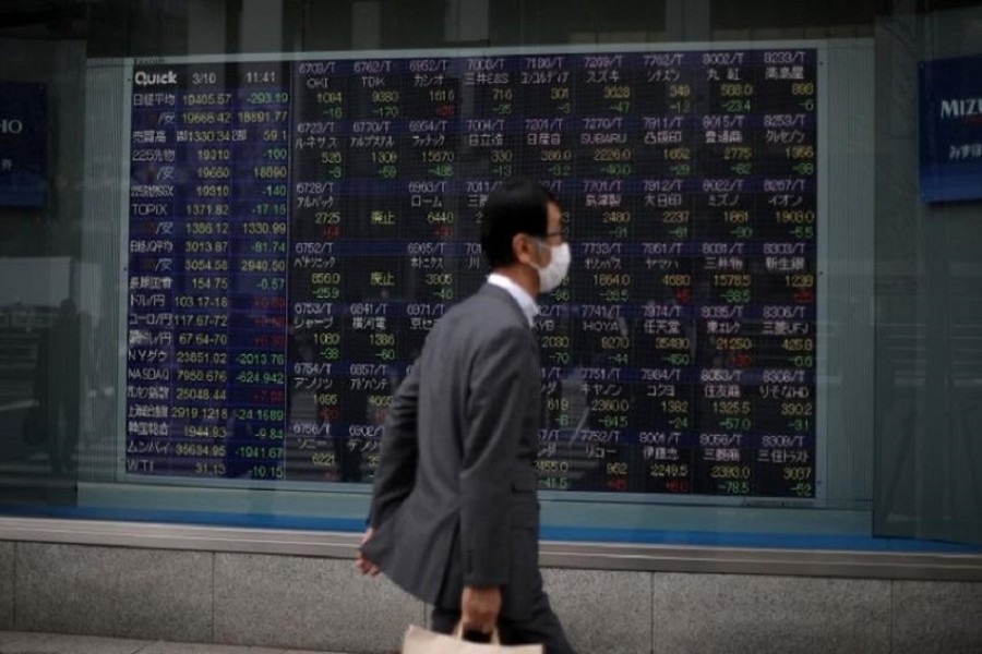 A man wearing a protective face mask, following an outbreak of the coronavirus disease (COVID-19), walks in front of a stock quotation board outside a brokerage in Tokyo, Japan, March 10, 2020 — Reuters/Files