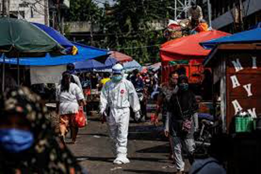 FILE PHOTO: A healthcare worker wearing protective gear walks through a traditional market as swab samples are collected from vendors to be tested for the coronavirus disease (COVID-19), in Jakarta, Indonesia, June 25, 2020. REUTERS/Willy Kurniawan