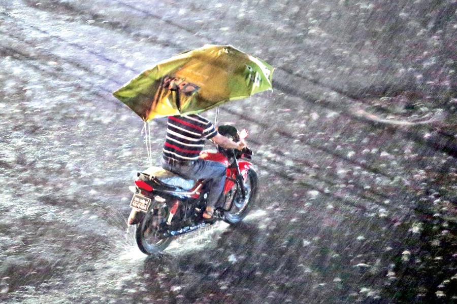 An innovative rider with a makeshift canopy added to his motorbike plying the road at Purana Paltan, February 26, 2018, during a sudden spell of rain that brings some relief for the city-dwellers — FE/Files