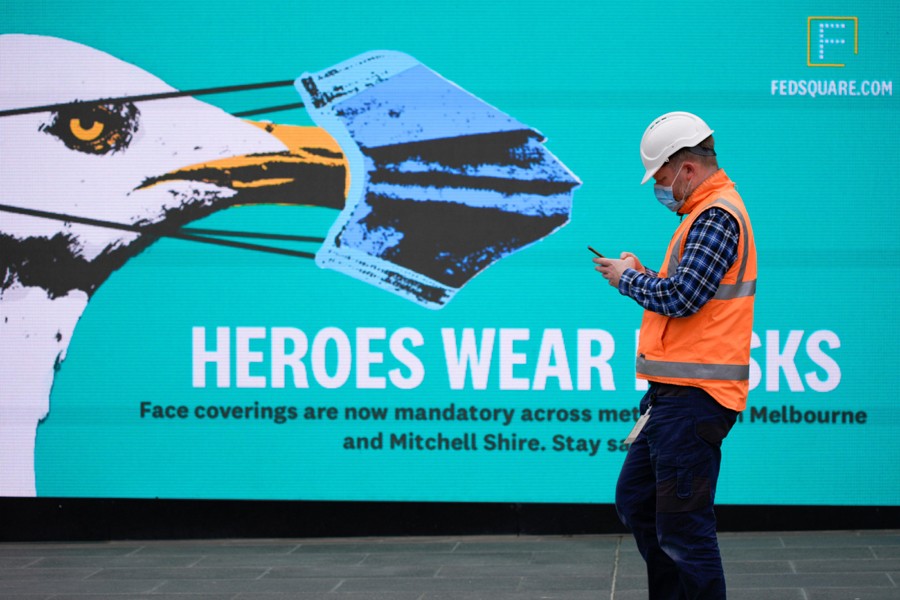 An essential worker wearing a face mask walks past a 'Heroes Wear Masks' sign in Melbourne after it became the first city in Australia to enforce mask-wearing in public as part of efforts to curb a resurgence of the coronavirus disease (Covid-19) on July 23, 2020 — Reuters photo