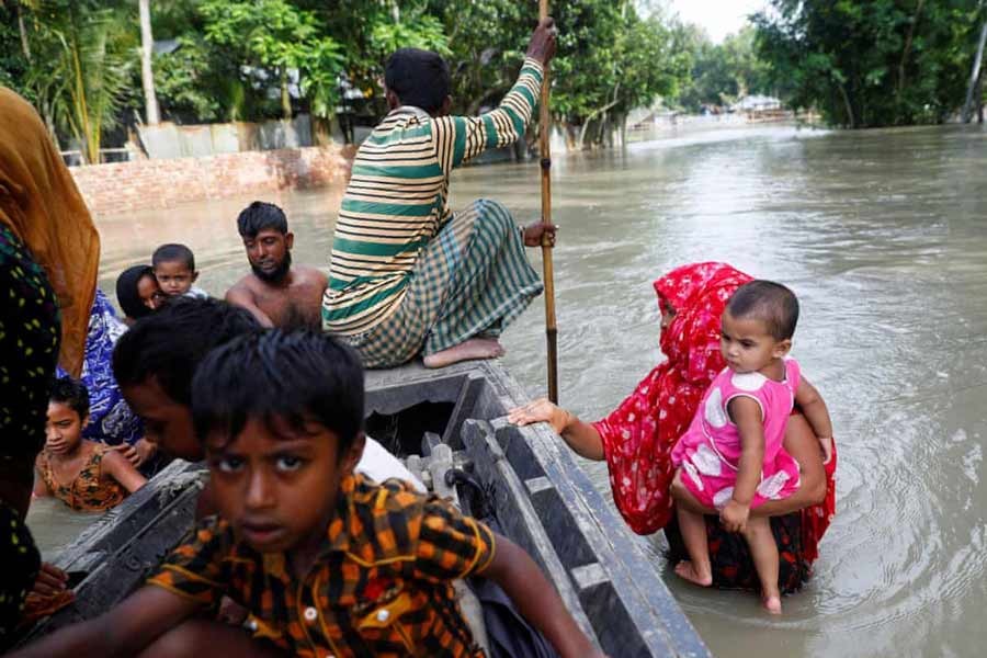 Flood-affected people crossing a stream on a boat in Jamalpur recently –Reuters Photo