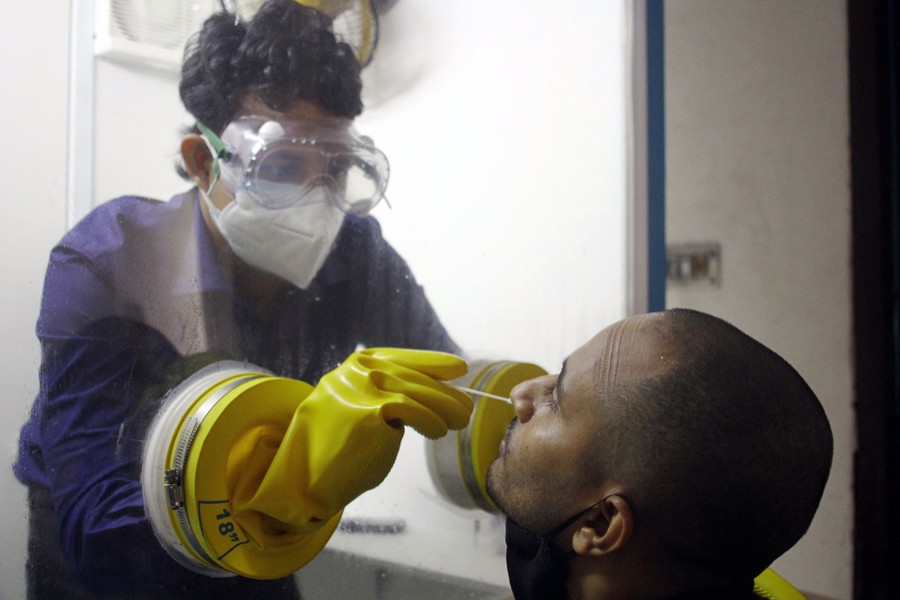 A healthcare worker in a protective chamber takes a swab sample from a man to test for Covid-19 disease at the National Press Club in the capital — File photo