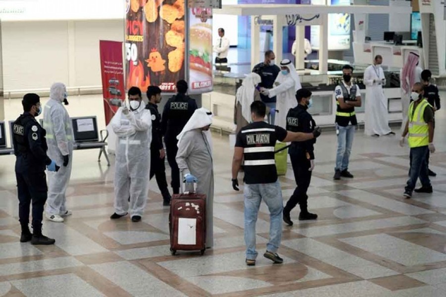 A Kuwaiti passenger holding his luggage walks by the police and civil aviation personnel upon his arrival from Amman at Kuwait Airport, following the outbreak of the coronavirus disease (Covid-19), in Kuwait City, Kuwait, April 21, 2020 — Reuters