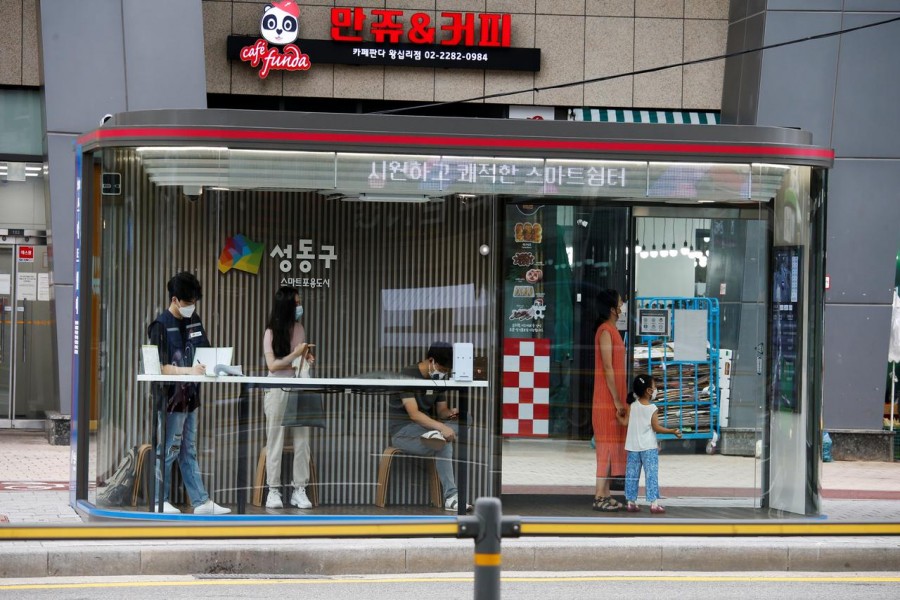 People wait for the bus inside a glass covered stop in which a thermal imaging camera, UV steriliser, air conditioner, CCTV and digital signage are set, to avoid the spread of Covid-19 in Seoul, South Korea on August 14, 2020 — Reuters/Files