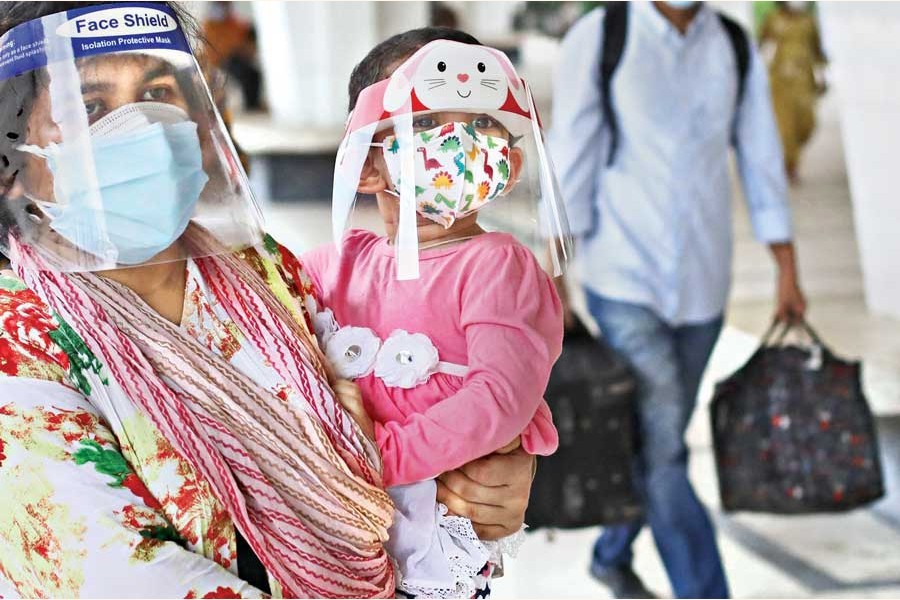 A mother and her child wear face shields and masks at the Kamalapur Railway Station in the city on Tuesday as they leave Dhaka with the coronavirus cases in the last 24 hours being the highest in the last one month — FE photo by Shafiqul Alam