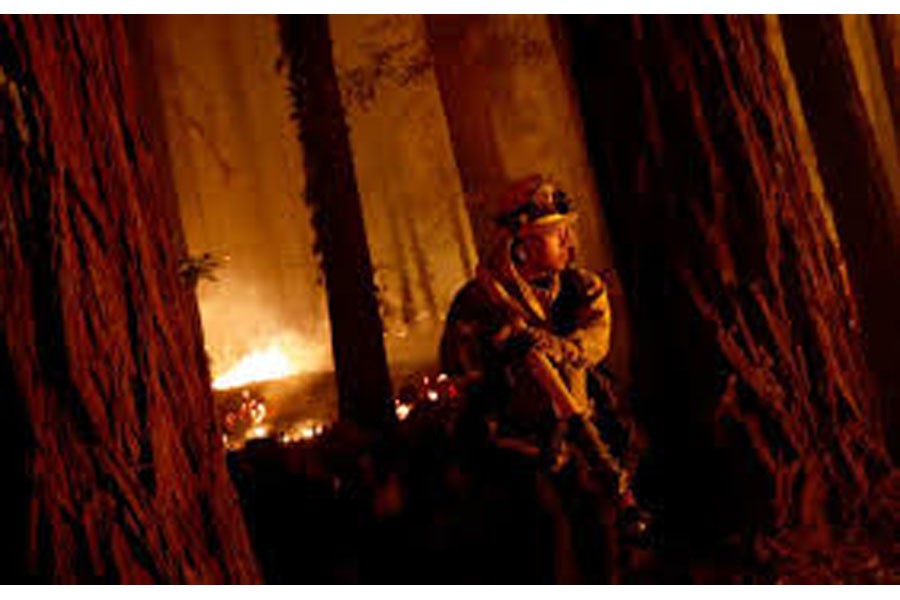 Cal Fire firefighter Anthony Quiroz carries a hose as he defends a home during the CZU Lightning Complex Fire in Boulder Creek, California, U.S. August 21, 2020. REUTERS/Stephen Lam