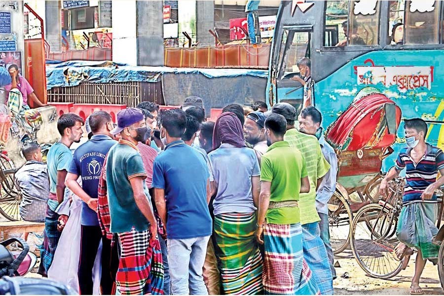 The photo shows a group of workers who were waiting on a roadside at Pallabi, Mirpur, in the city to be hired for work mob a man looking for labourers on Wednesday —FE photo by KAZ Sumon