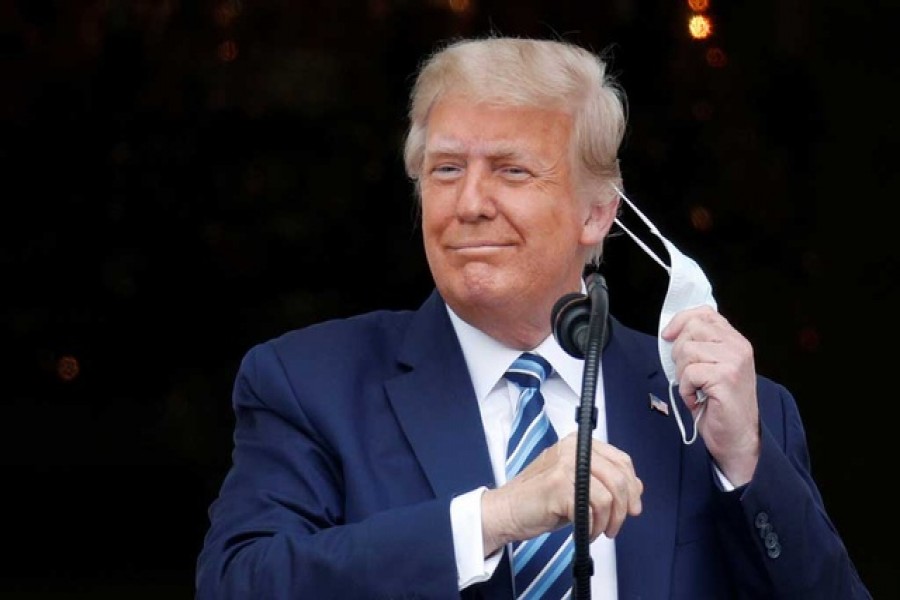 US President Donald Trump takes off his face mask as he comes out on a White House balcony to speak to supporters gathered on the South Lawn for a campaign rally that the White House is calling a "peaceful protest" in Washington, US, October 10, 2020 — Reuters