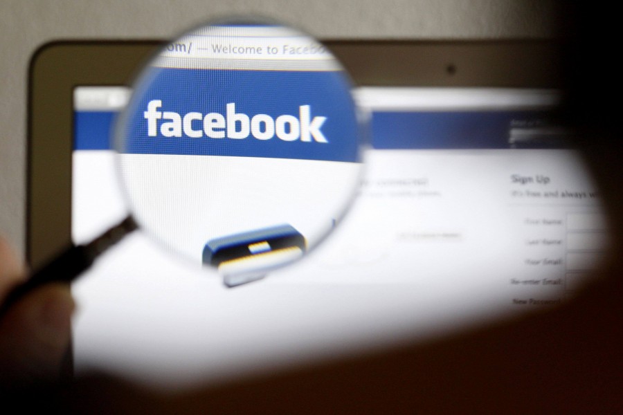 In this photo illustration, a Facebook logo on a computer screen is seen through a magnifying glass held by a woman in Bern on May 19, 2012. Picture taken on May 19, 2012 — Reuters/Files