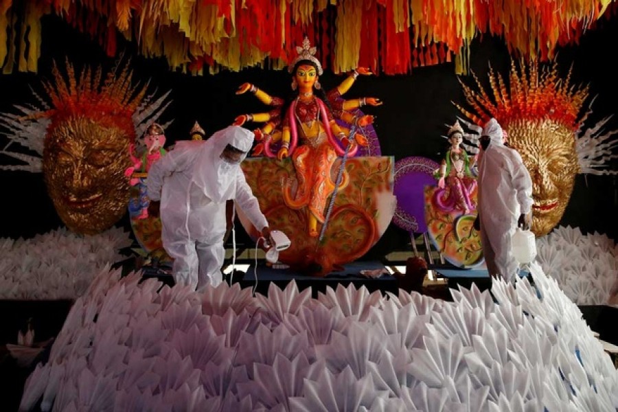 People wearing personal protective equipment (PPE) sanitise a "pandal" or a temporary platform, next to an idol of Hindu goddess Durga for the upcoming of Durga Puja festival, amidst the spread of the coronavirus disease (COVID-19), in Kolkata, India, October 12, 2020. REUTERS