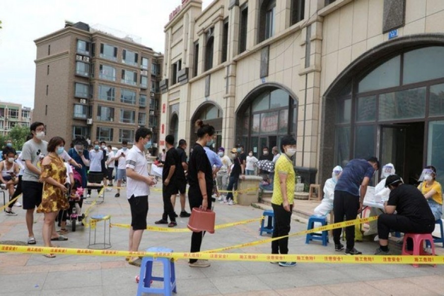 Residents wearing face masks line up to receive nucleic acid tests after new cases of coronavirus disease (COVID-19) were confirmed in Dalian, Liaoning province, China July 26, 2020. cnsphoto via REUTERS