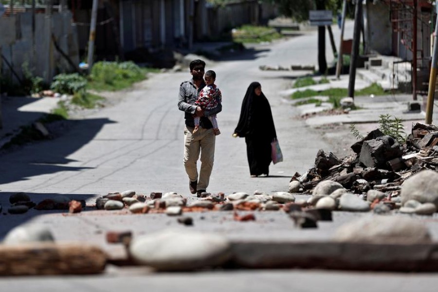 A Kashmiri family walks past a blockade put up by residents to prevent Indian security force personnel from entering their neighbourhood during restrictions, after the scrapping of the special constitutional status for Kashmir by the Indian government, in Srinagar on August 20, 2019 — Reuters/Files