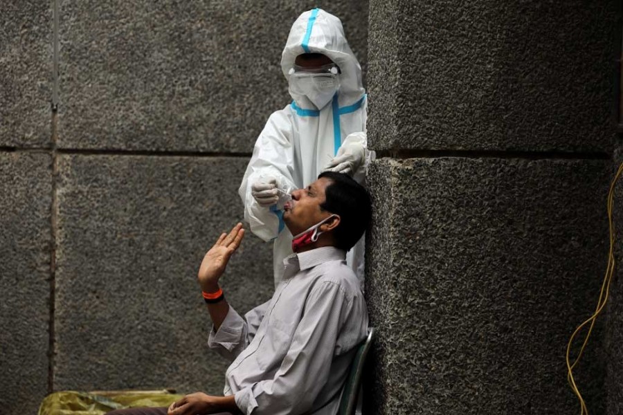 A healthcare worker wearing personal protective equipment (PPE) collects a swab sample from a man amidst the spread of the coronavirus disease (Covid-19), at a testing center in New Delhi, India on October 29, 2020 — Reuters photo