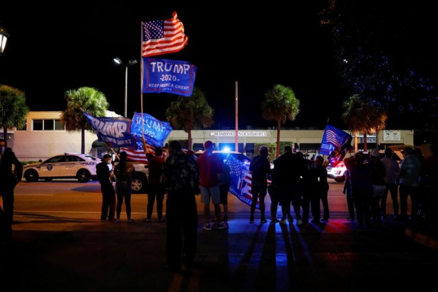 Supporters of US President Donald Trump hold flags during the 2020 US presidential election, outside Versailles Restaurant at Little Havana neighbourhood in Miami, Florida, US, November 3, 2020. REUTERS/Marco Bello