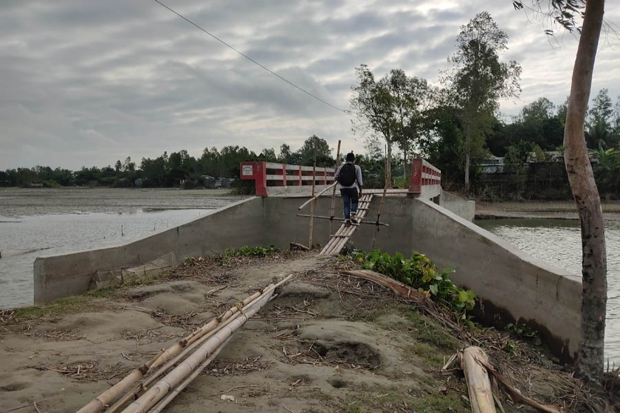 A man uses a bamboo bridge to access the concrete bridge on Ruposhi-Pakurtala road in Ghatabari area of Jalalpur union in Shahjadpur upazila of Sirajganj — FE Photo/Files