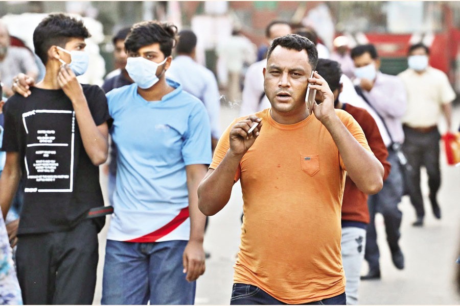 Wrong on two counts: A pedestrian with no mask on his face is seen smoking in a public place unaware of the legal bars prohibiting both. The photo was taken on Wednesday at Bangabandhu Avenue in the city. — FE Photo by Shafiqul Alam