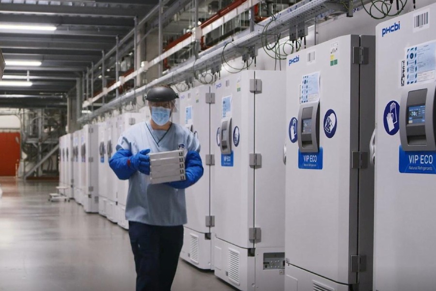 A worker passes a line of freezers holding coronavirus disease (Covid-19) vaccine candidate BNT162b2 at a Pfizer facility in Puurs, Belgium in an undated photograph. Pfizer/Handout via REUTERS.