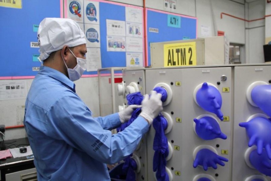 A worker inspects newly made gloves at Top Glove factory in Klang, Malaysia, March 3, 2020. Picture taken March 3, 2020. Top Gloves/Anas Zakwan/Handout via REUTERS