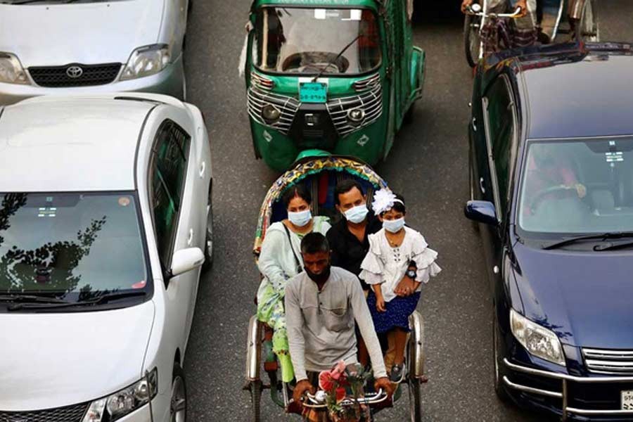 People wearing protective masks while riding on a rickshaw in Dhaka. The photo was taken on November 19. –Reuters file photo